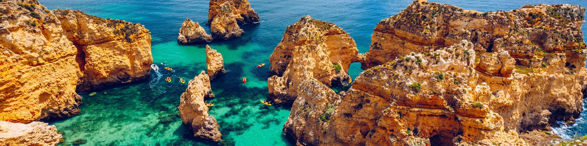 Panoramic view, Ponta da Piedade near Lagos in Algarve, Portugal. Cliff rocks and tourist boat on sea at Ponta da Piedade, Algarve region, Portugal. Ponta da Piedade, Algarve region, Portugal.