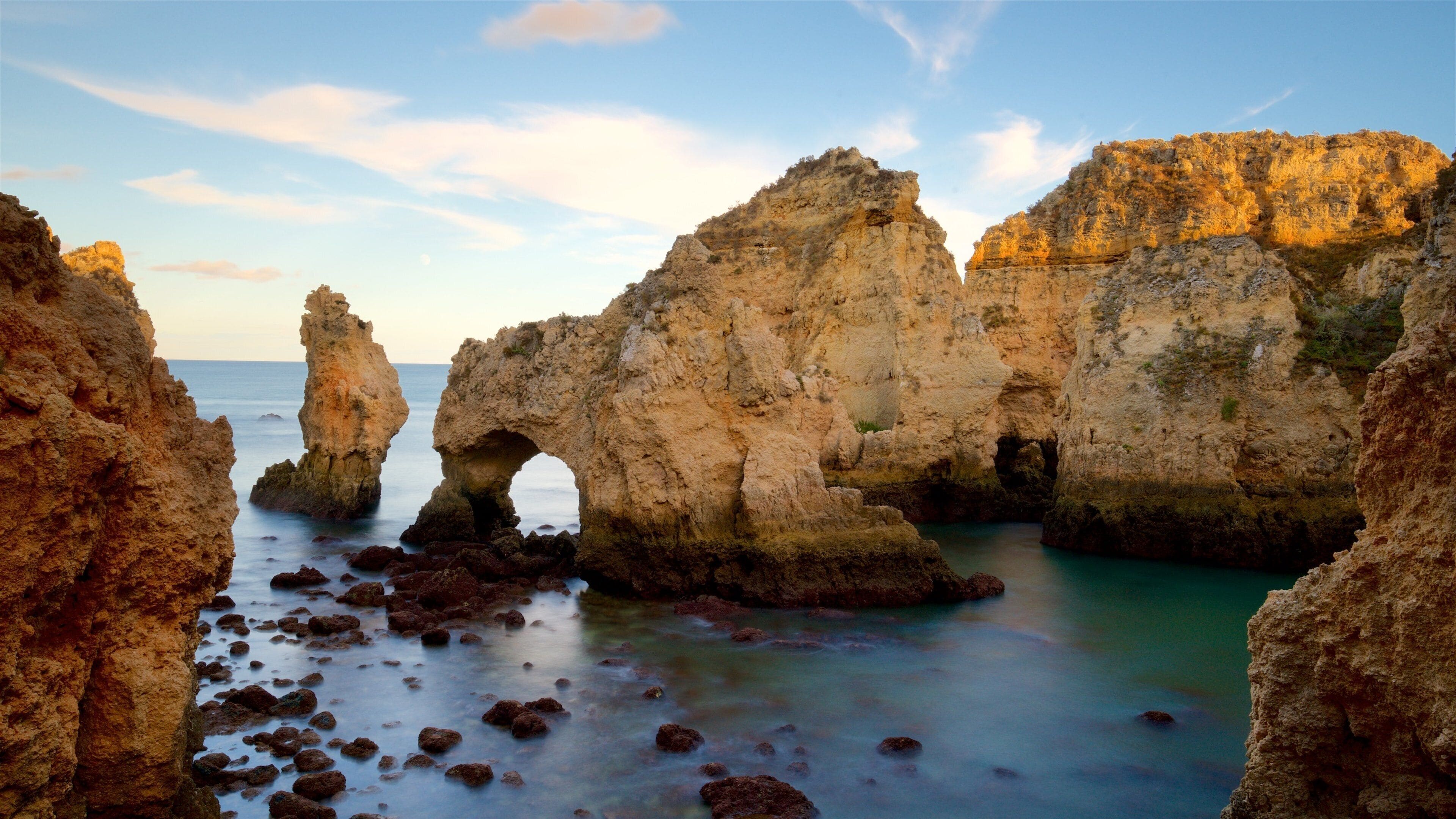 A coastal landscape with rocky formations and a clear blue sky.