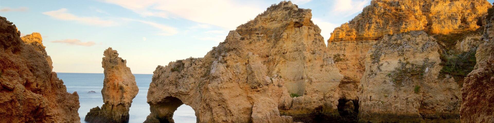 A coastal landscape with rocky formations and a clear blue sky.