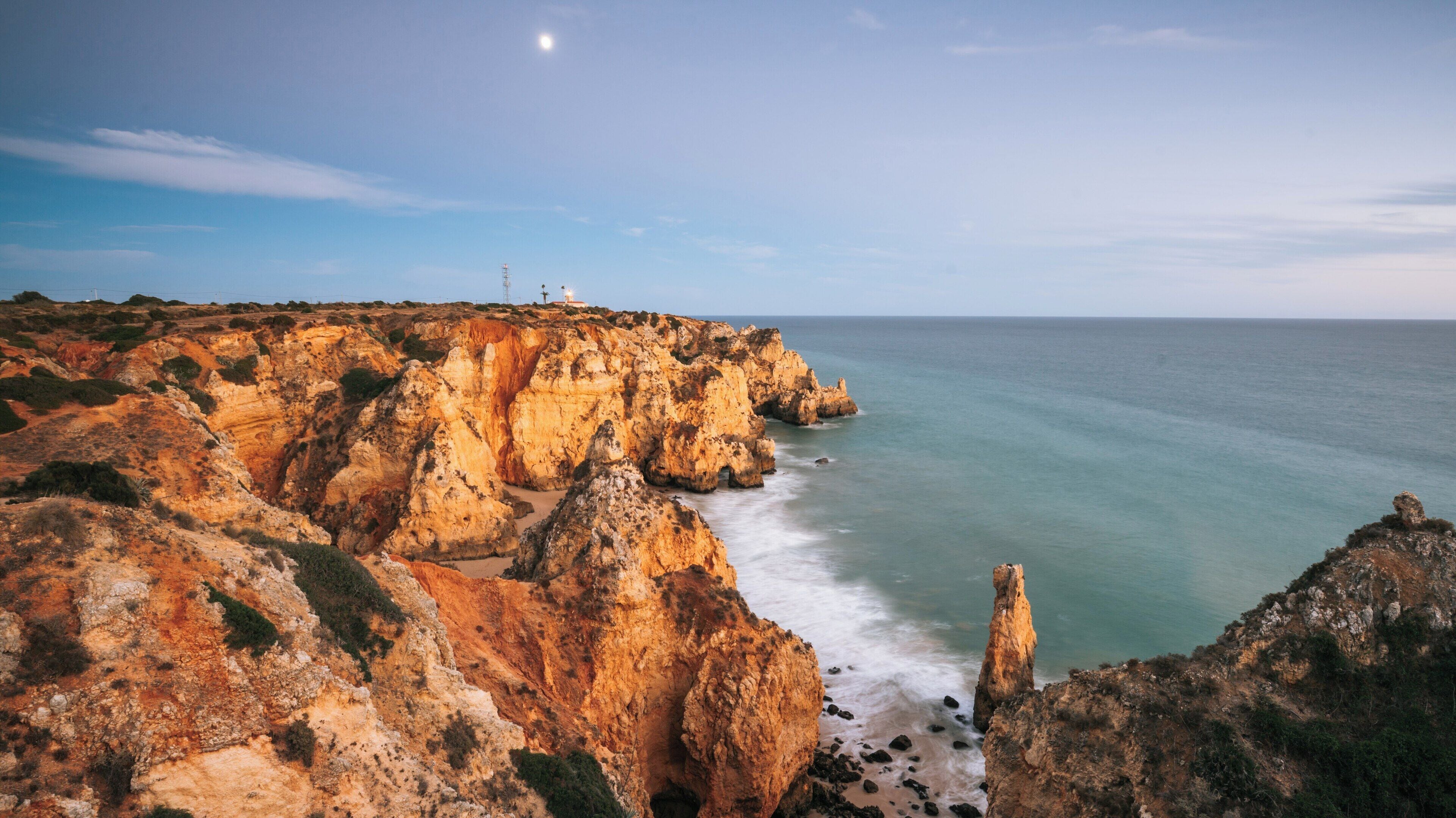 Ponta da Piedade Lagos Lighthouse stands majestically along the stunning cliffs of Faro District in Portugal, illuminating the coastline at dusk