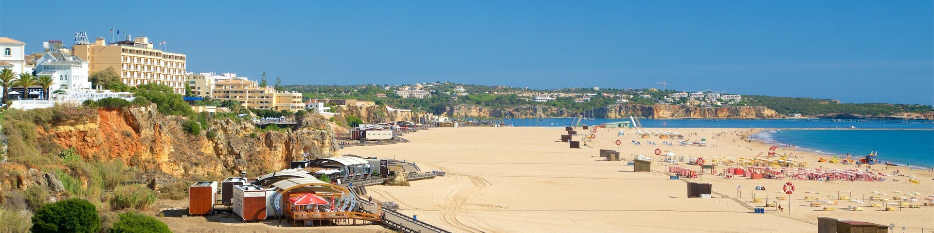 Una playa costera con arena, sombrillas y un restaurante llamado 'Spot 3'.