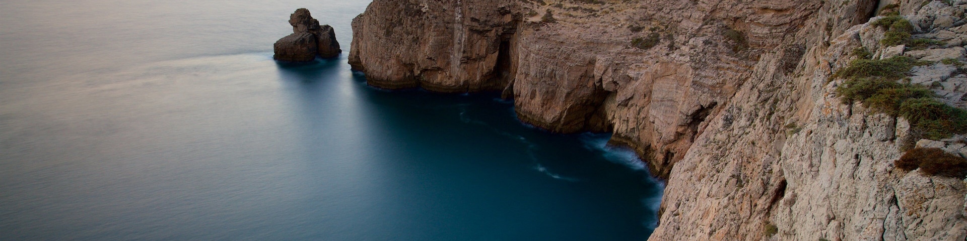 Farol do Cabo de São Vicente caracterizando litoral rochoso, paisagens litorâneas e um pôr do sol