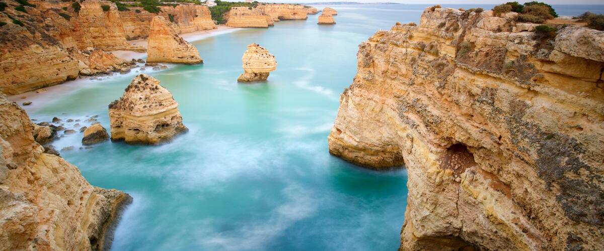 A coastal landscape with prominent rock formations and a calm sea.