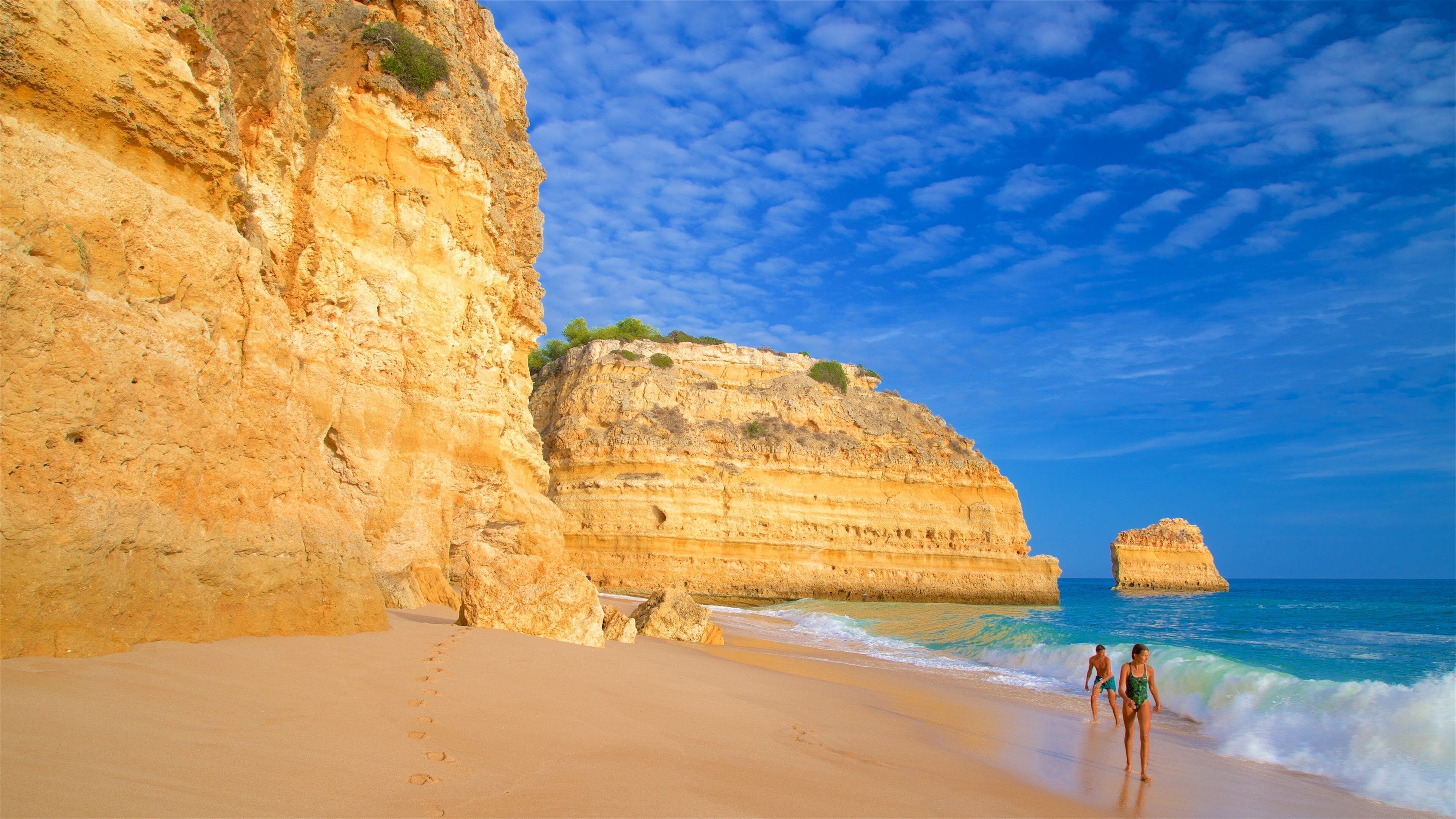 Marinha Beach featuring waves, a beach and rugged coastline