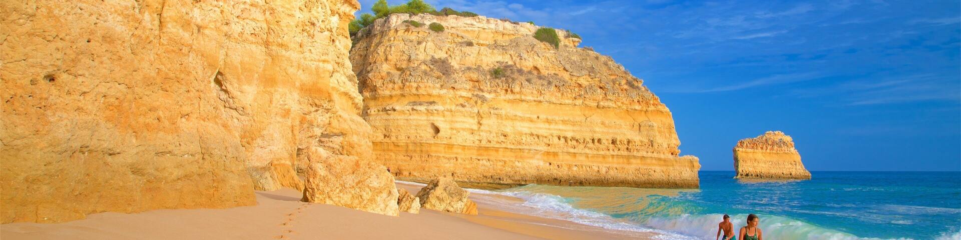 Marinha Beach featuring waves, a beach and rugged coastline
