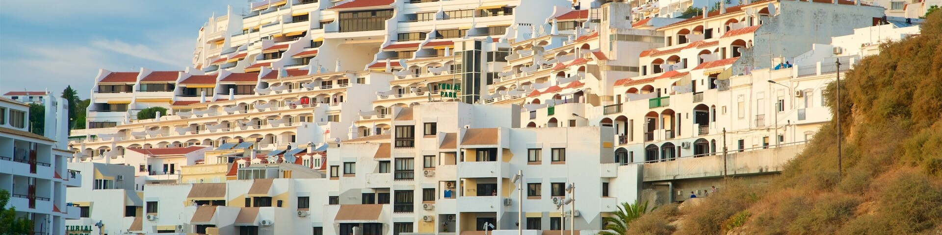 A coastal town with multi-story buildings, a sandy beach, and a rocky hillside.