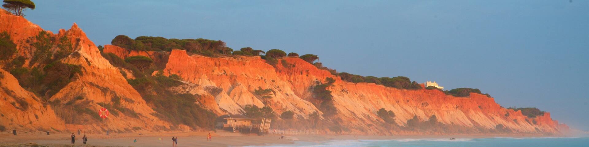A beach with red cliffs and calm waters.