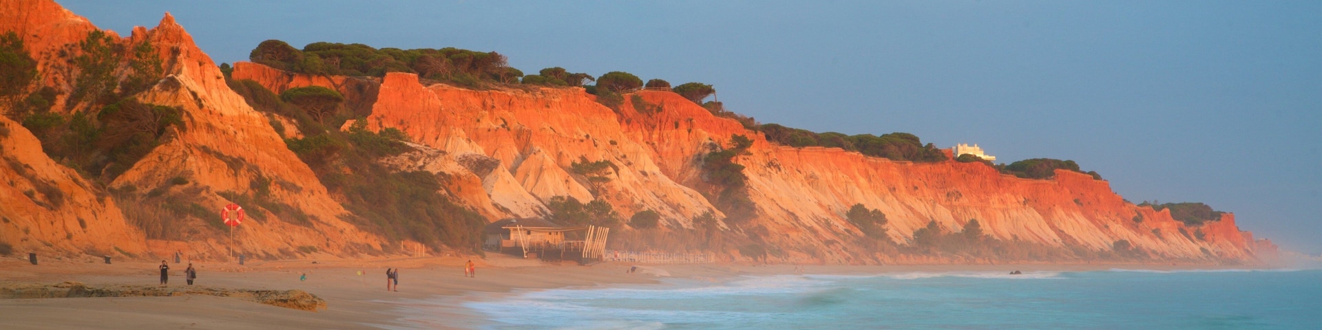 Una playa con acantilados rojos y aguas tranquilas.