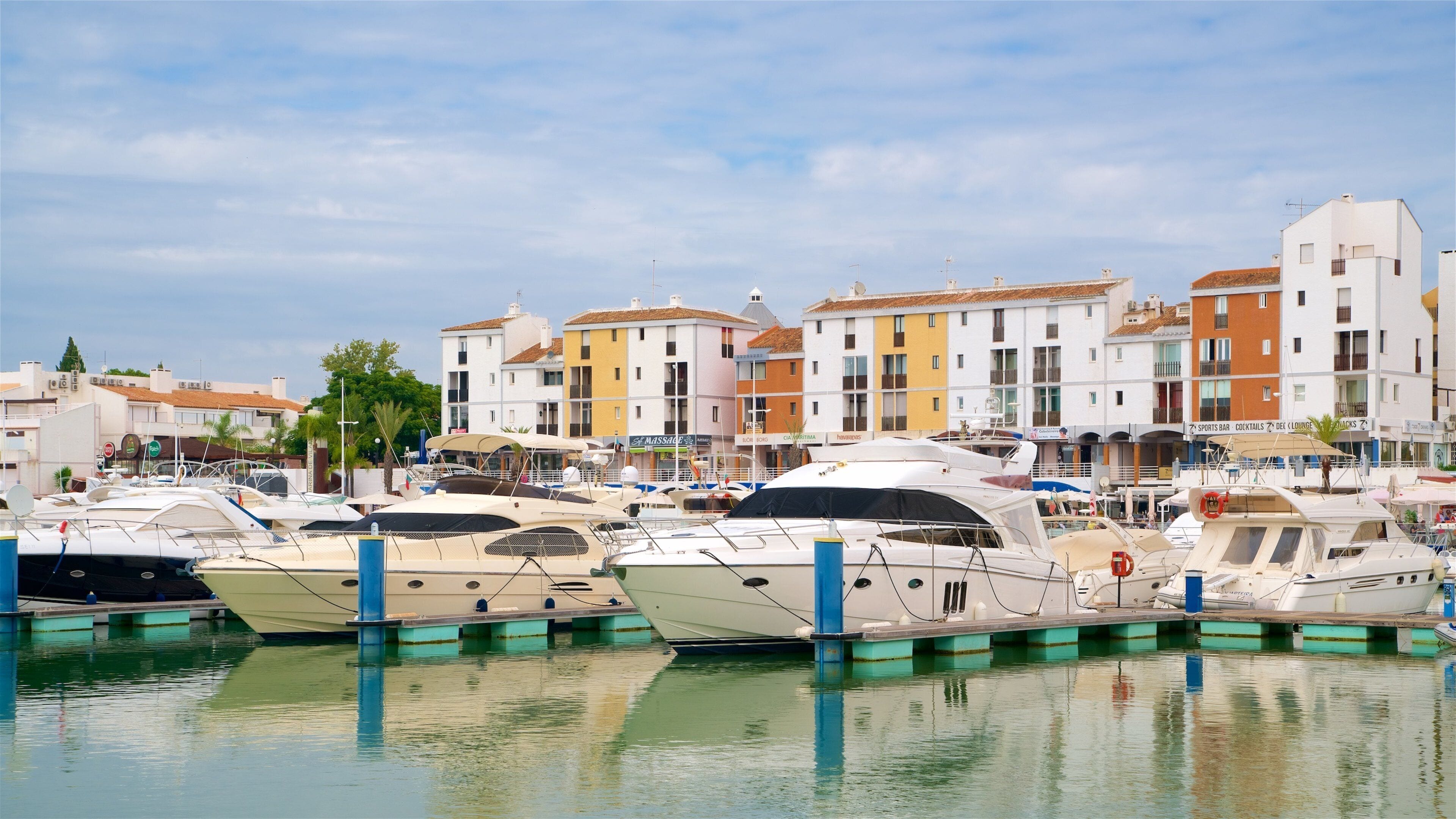 Eine Marina mit mehreren angossenen Yachten, umgeben von bunten Gebäuden und blauem Himmel.