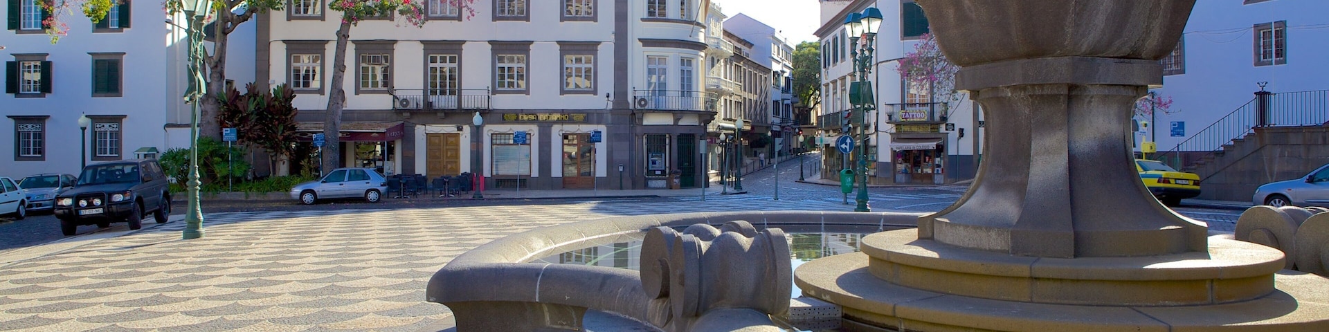 A fountain in a square with buildings in the background.