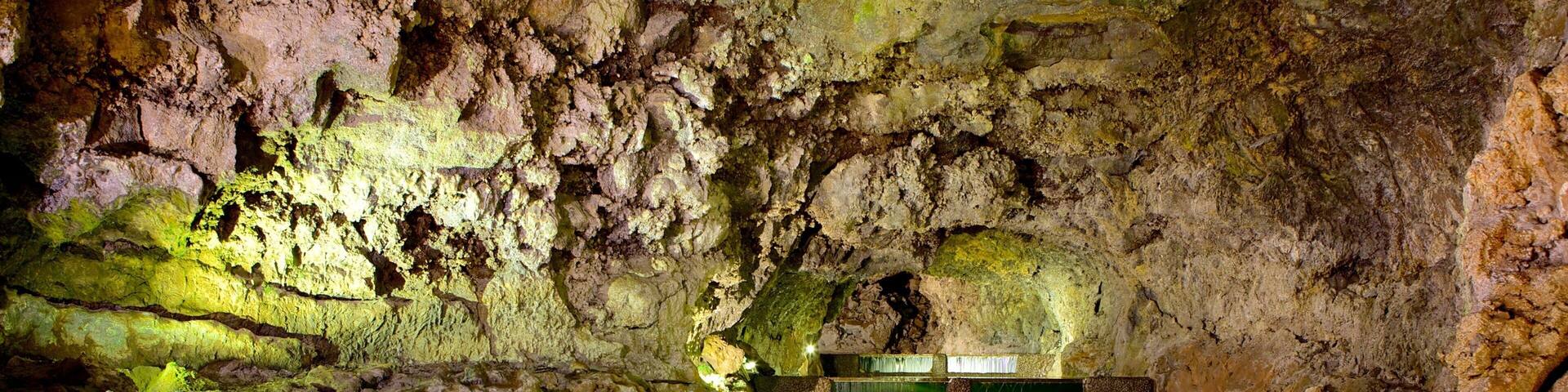 Una cueva con un estanque de agua y un banco.
