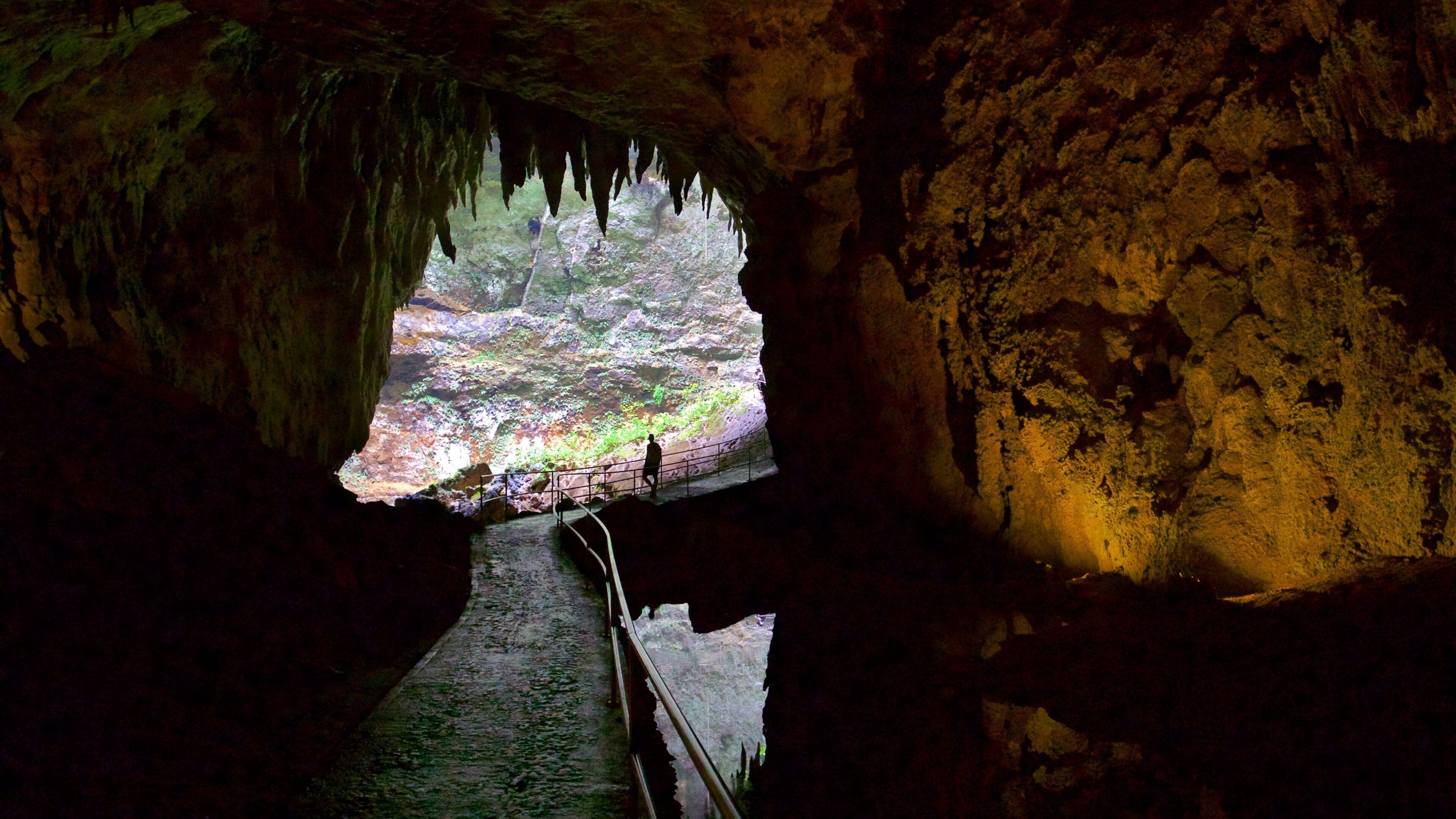 A cave with a natural rock bridge and a person standing on it.