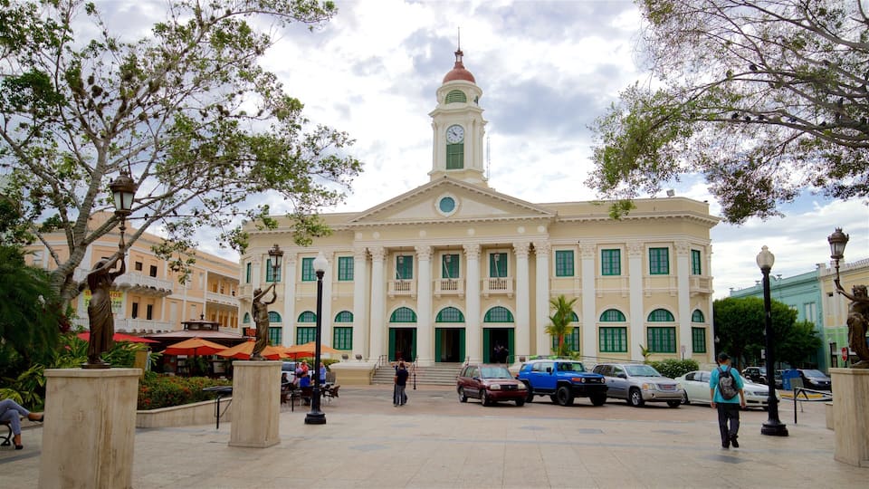 A historic building with a clock tower, surrounded by trees and outdoor seating areas.