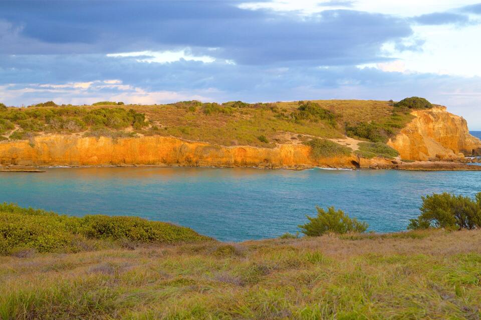 Paisagem costeira com um penhasco e um mar calmo.