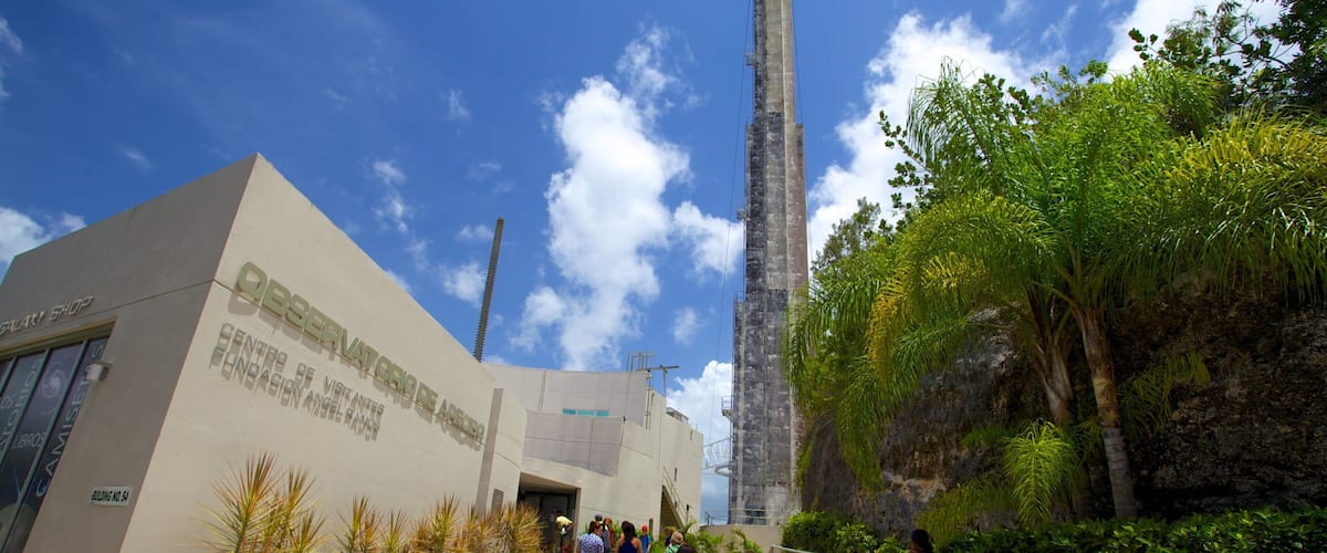 A modern building with a sign reading "Observatorio de Arecibo" and a tall tower.