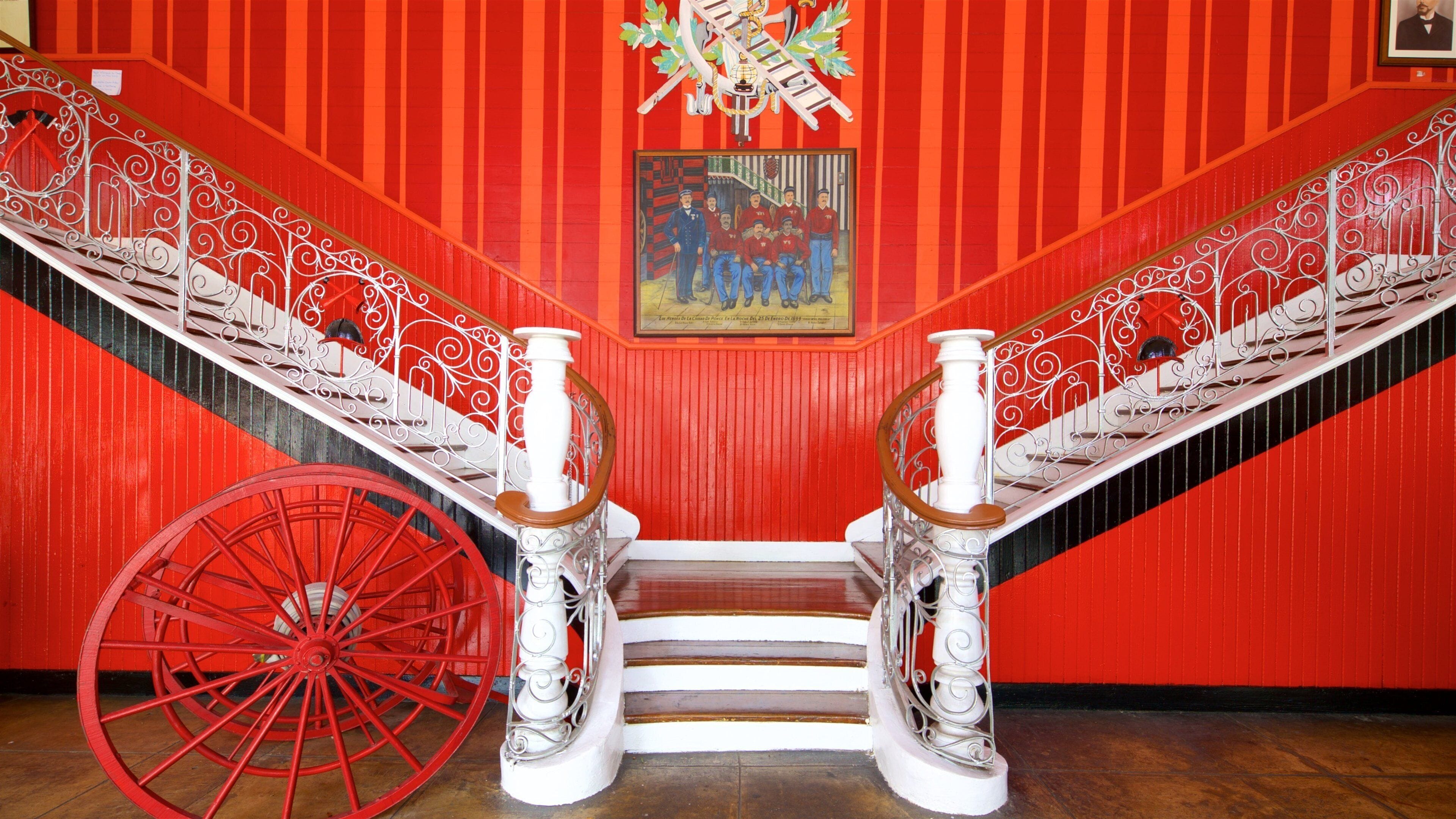A red staircase with ornate white railings and a red carriage wheel.
