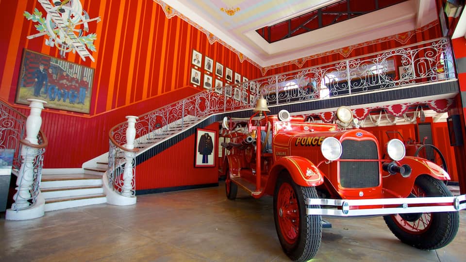 A vintage fire engine in a museum with red walls and a staircase.