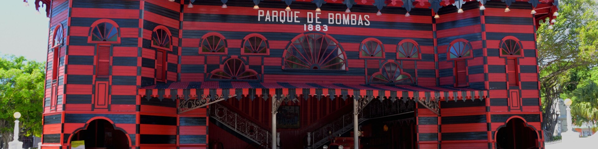 Un edificio de rayas rojas y negras con una cúpula y la inscripción 'Parque de Bombas 1883'.