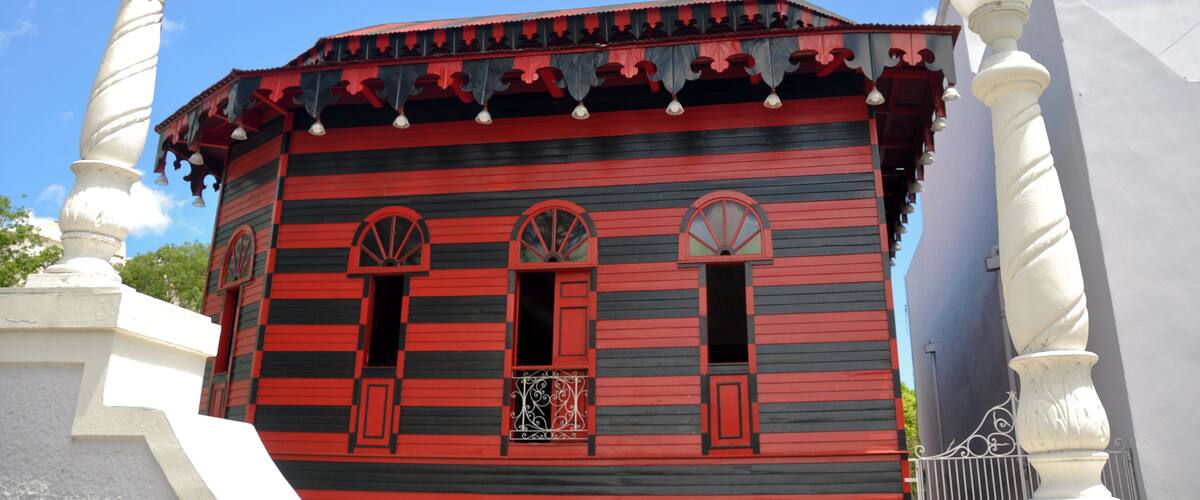 A building with red and black striped walls, arched windows, and white decorative columns.