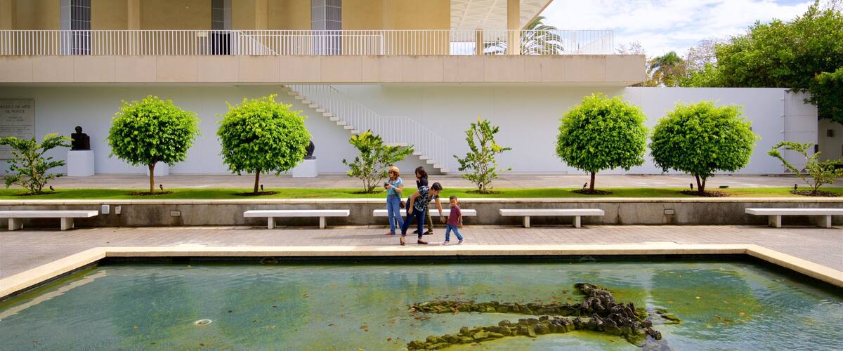 A modern building with a geometric roof, a central courtyard with a pool, and several small trees.