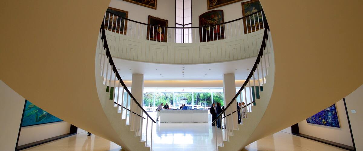 Ein geräumiger Atrium mit hoher Decke, einer zentralen Treppe und Kunstwerken an den Wänden.