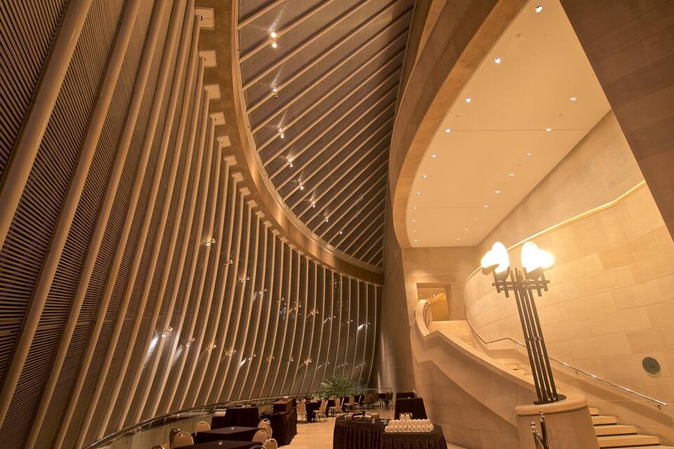 Een modern interieur met een gebogen trap, een versierd plafond en een kroonluchter.