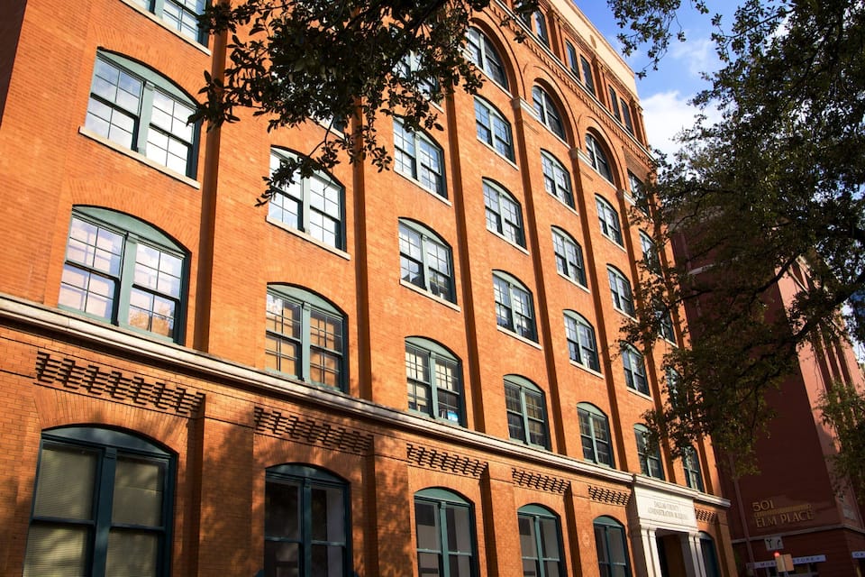 A red brick building with multiple windows and a sign that reads "Dallas County Administration Building".