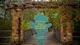 A sign welcoming visitors to the Texas Native Forest Boardwalk, with a wooden archway and a leaf-shaped sign.