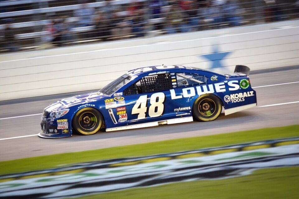 A blue race car with the number 48 and "LOWE'S" on the side, driving on a track.