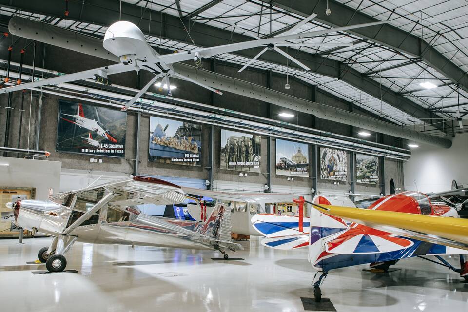 Museu com diversas aeronaves expostas, incluindo um caça e um biplano.