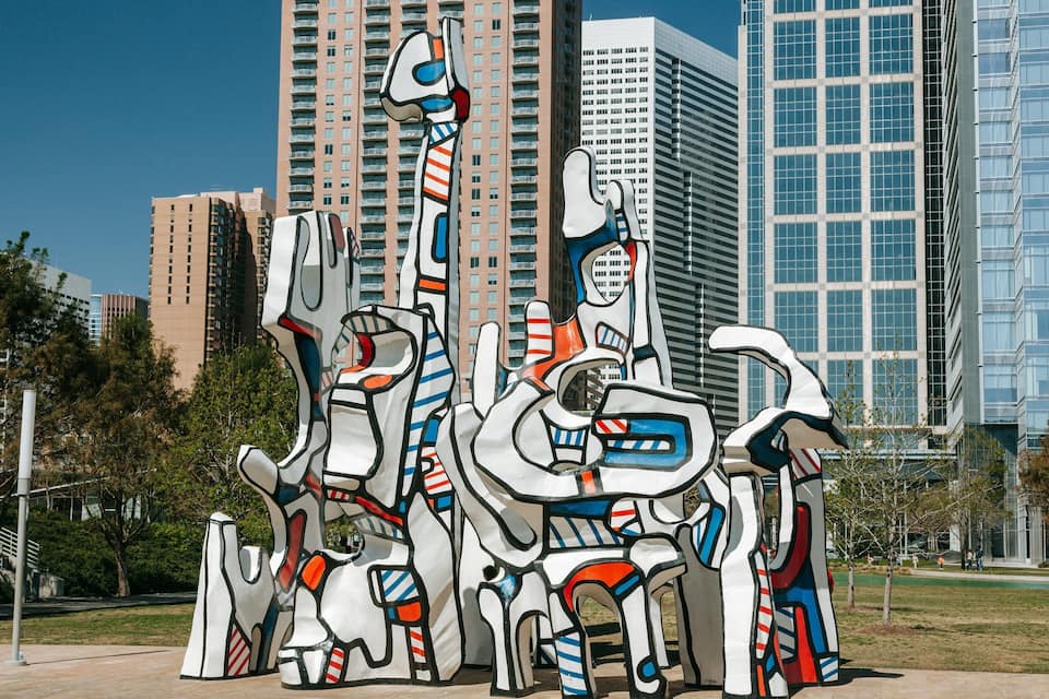 Jardí d'escultures amb obres d'art abstractes davant edificis moderns.