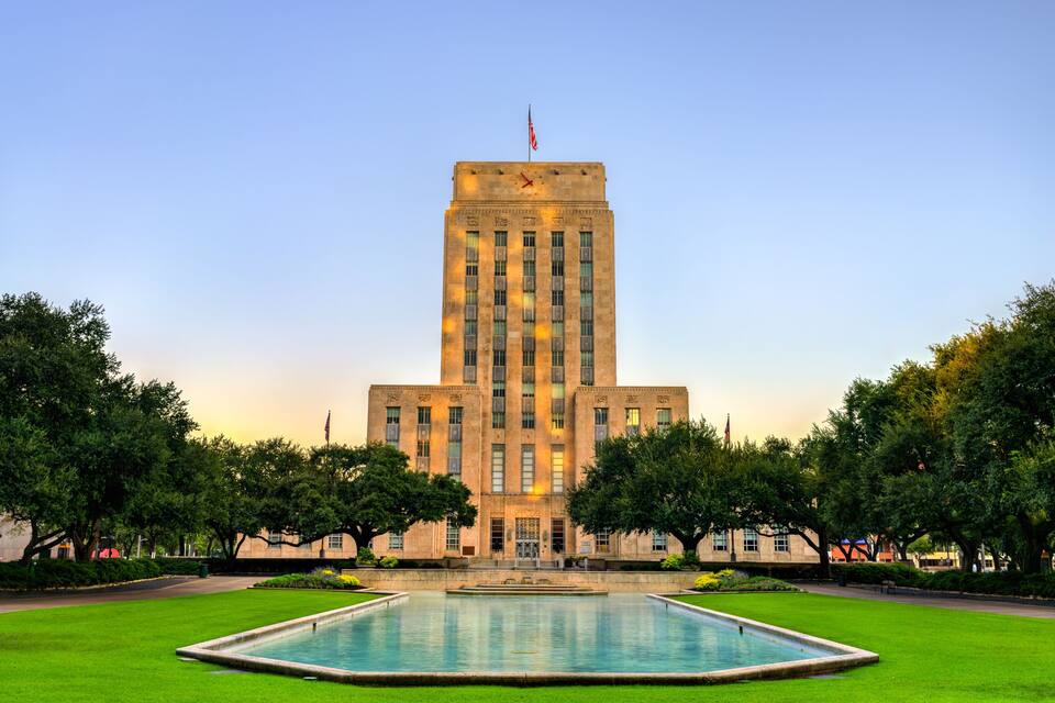 Un edificio grande e histórico con un patio central y una bandera en la cima.