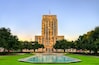 Houston City Hall viewed from Hermann Square, illuminated by warm sunrise light. The reflecting pool in the foreground mirrors the clear sky