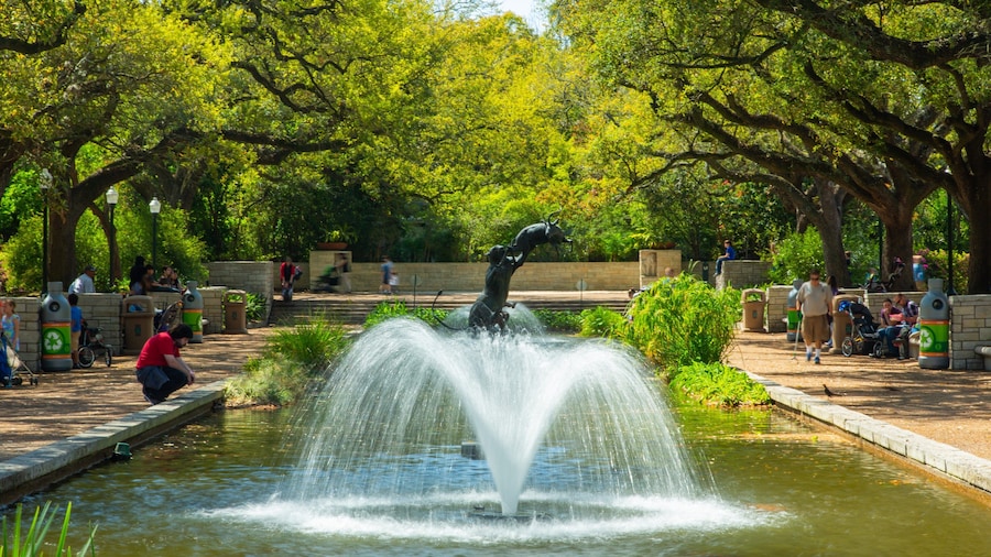 Fountain and animal sculpture at Houston Zoo surrounded by trees and visitors enjoying the shaded pathways.