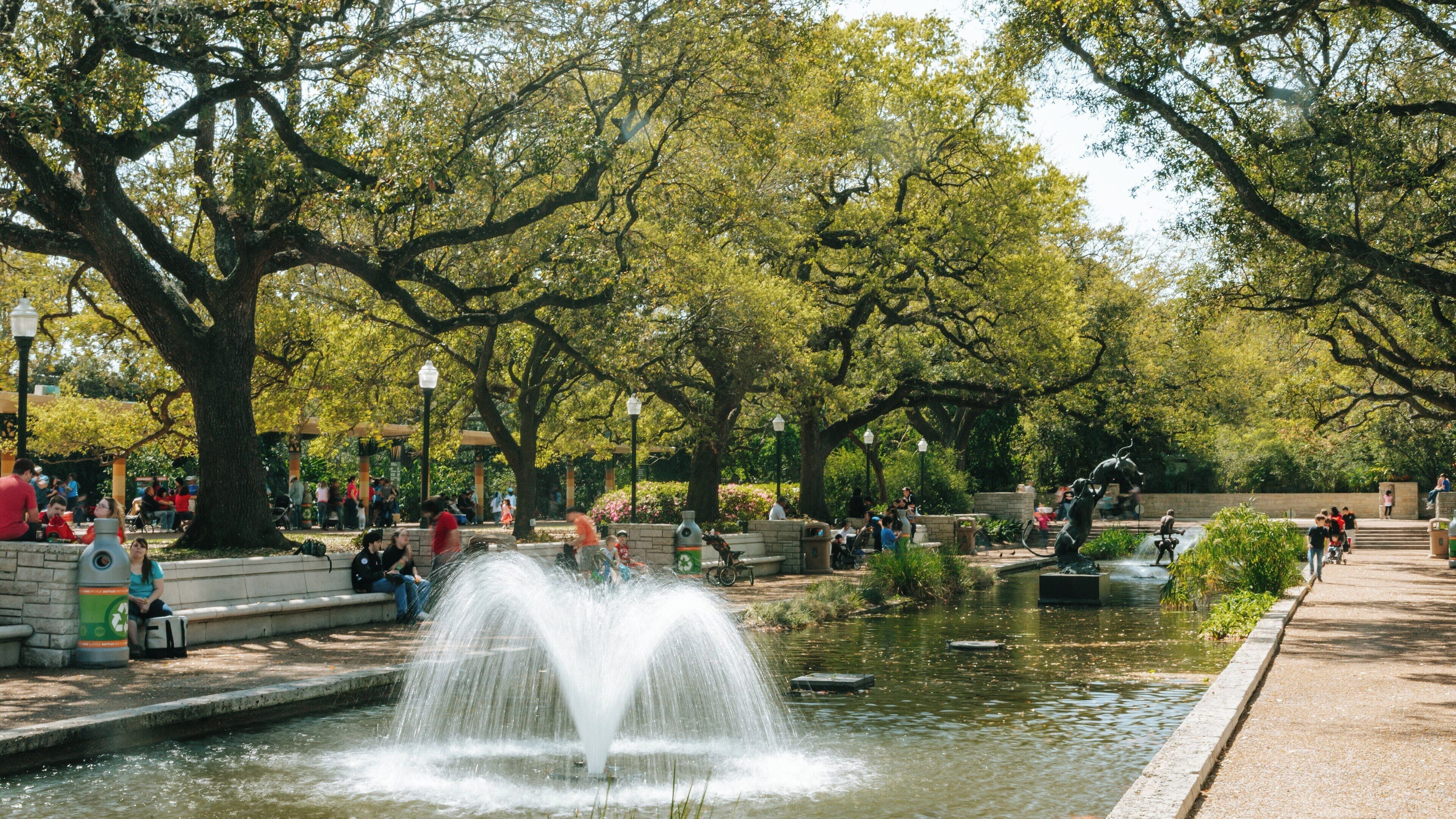 Visitors enjoy a sunny day at Houston Zoo's picturesque landscape with a beautiful fountain in the heart of the Museum District
