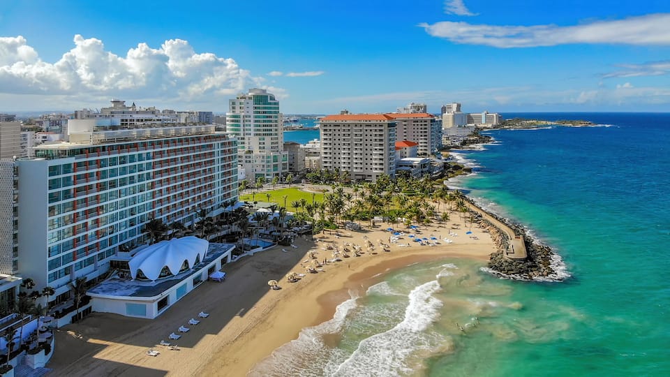 A coastal cityscape with a beachfront, high-rise hotels, and a clear blue sky.