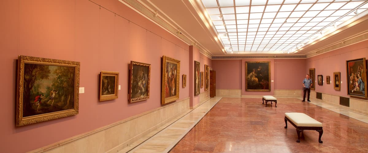 A museum corridor with marble floors and paintings on the walls.