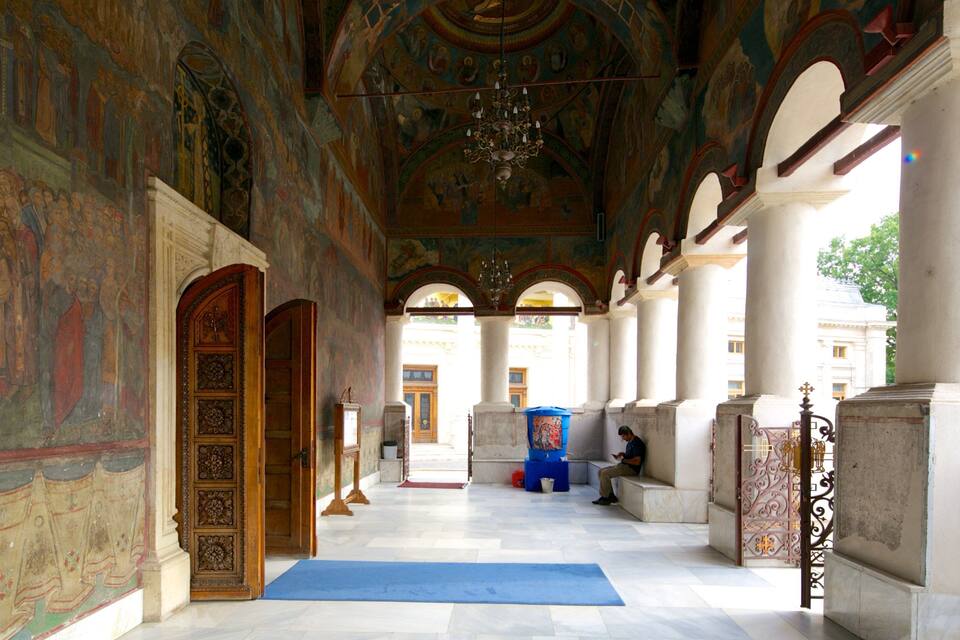 An interior with ornate murals, columns, and a chandelier.