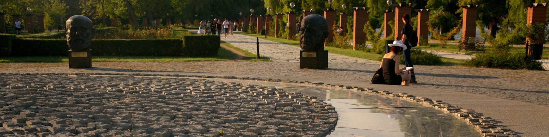 A star-shaped paved area with statues and a pathway lined with trees.