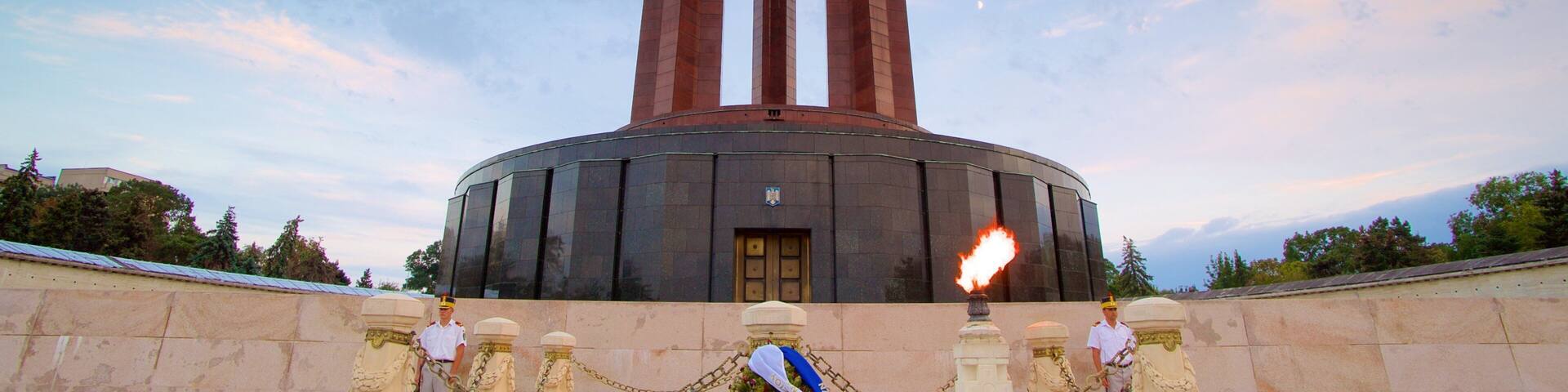 Parque Carol caracterizando um pôr do sol e um monumento assim como um pequeno grupo de pessoas