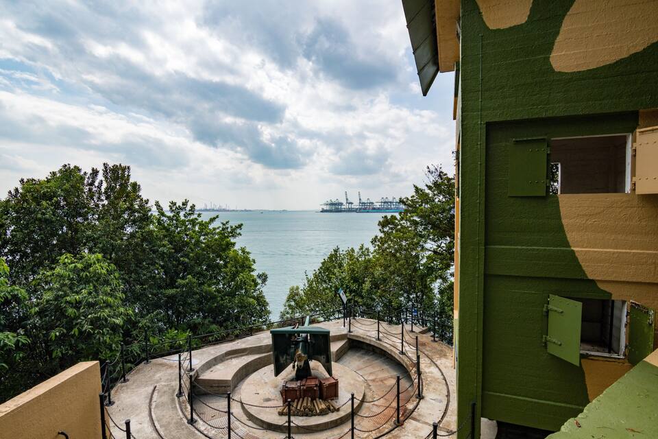 A waterfront view with a green building, trees, and a distant ship.