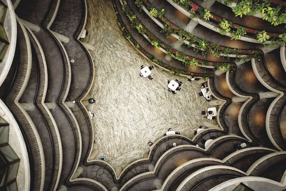 A spiral staircase with multiple levels, each with a seating area and greenery.