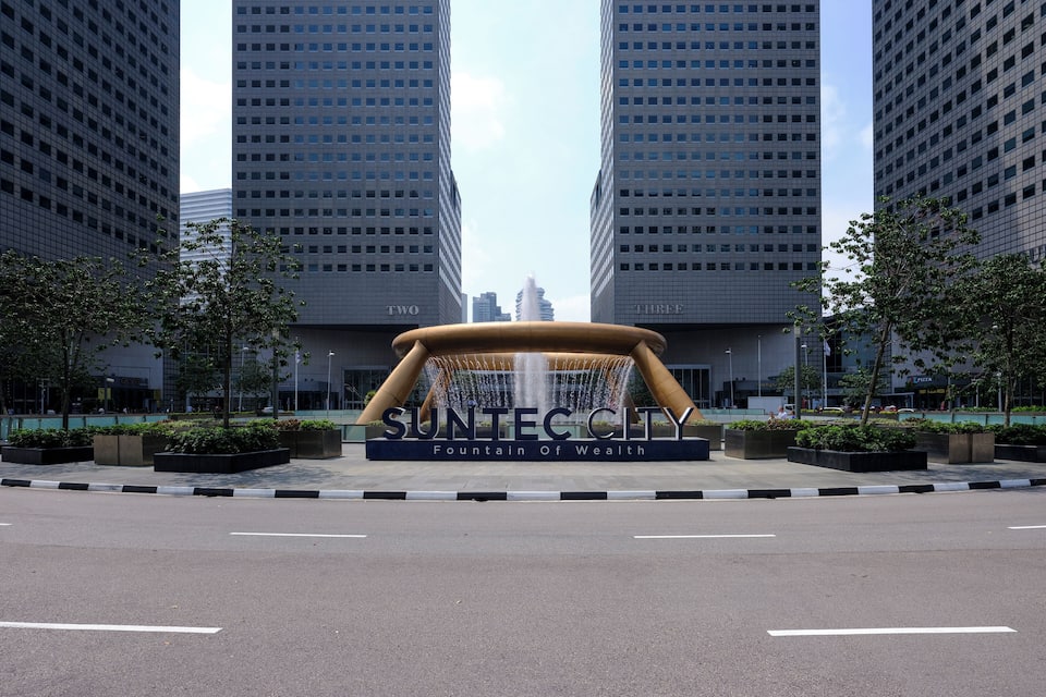 A modern urban plaza with a central fountain labeled "SuntecCity" and two tall buildings flanking it.