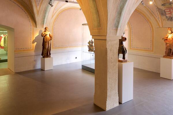 Ein Museuminnenraum mit klassischen Statuen und aufwendigen Deckenverzierungen.