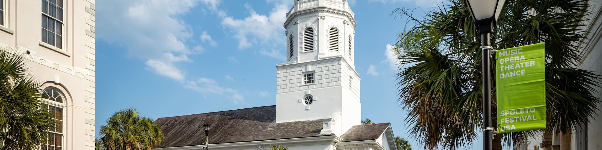 A historic building with a clock tower, a horse-drawn carriage, and a sign for the Spoleto Festival USA.