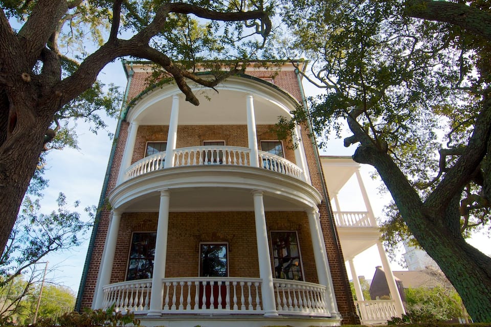A two-story brick building with a white balcony and columns.