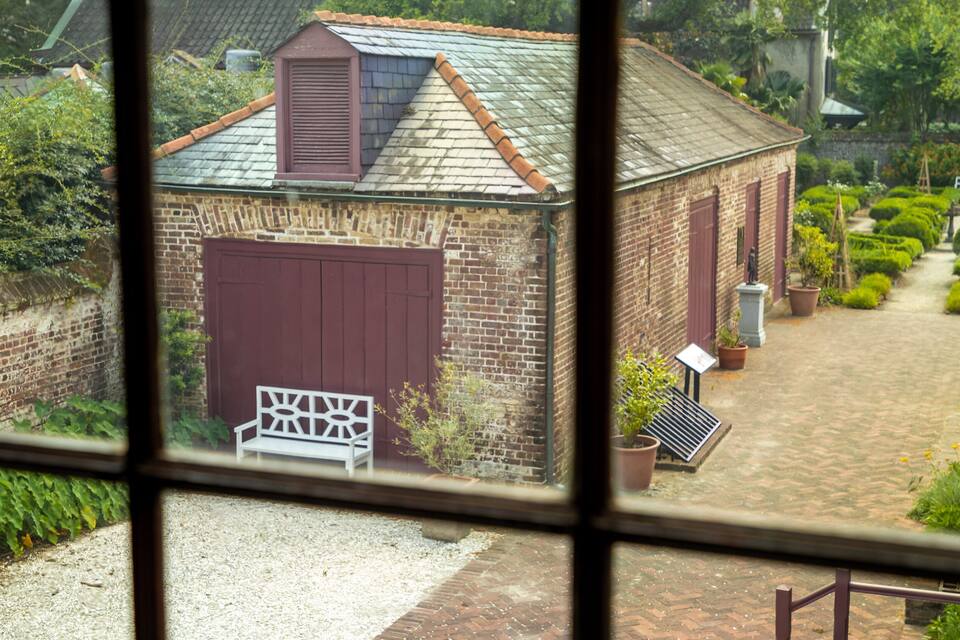 A brick building with a red door and a white bench in front.
