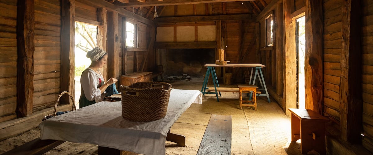 A rustic wooden interior with a table, a basket, and a painting on easels.