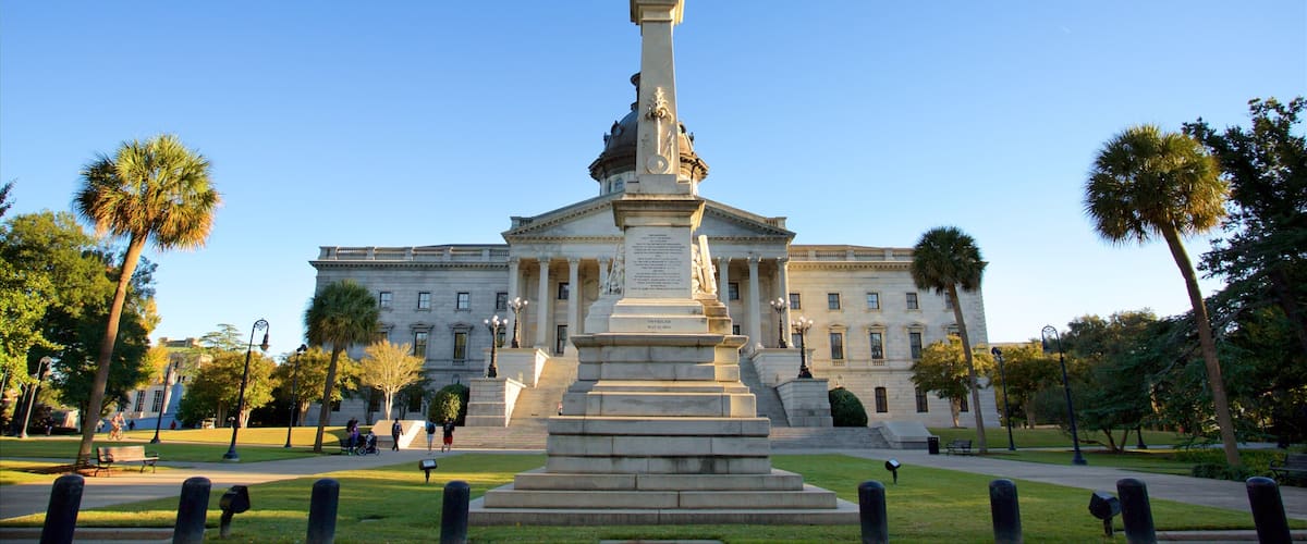 A monument with a statue on top, in front of a large building with columns.