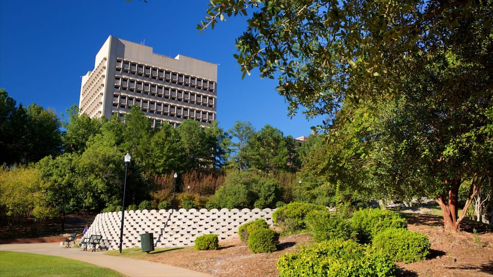 A modern building with a grid-like facade, surrounded by lush greenery and a patterned wall.